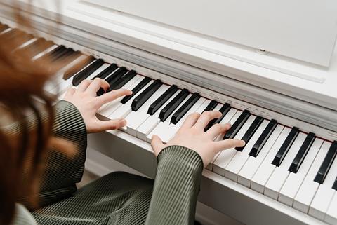 A close-up of a woman playing music on a white piano.
